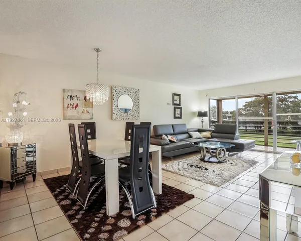 a view of a dining room and livingroom with furniture wooden floor a rug a fireplace and a chandelier