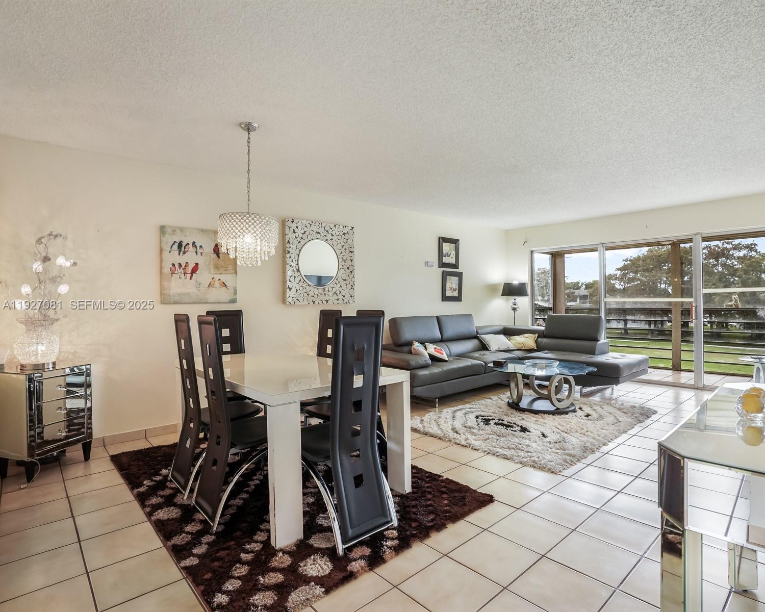a view of a dining room and livingroom with furniture wooden floor a rug a fireplace and a chandelier