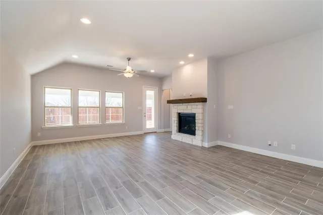 an empty room with a chandelier fan and windows