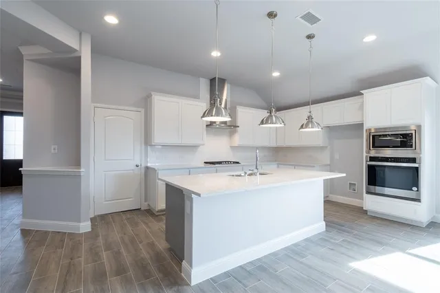 a kitchen with kitchen island a sink stainless steel appliances and cabinets