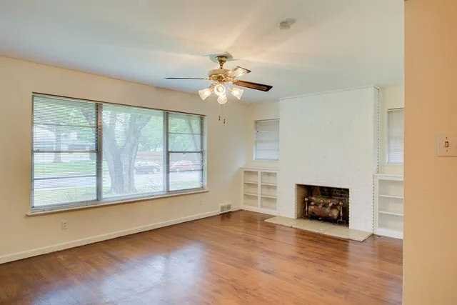 wooden floor fireplace and windows in an empty room