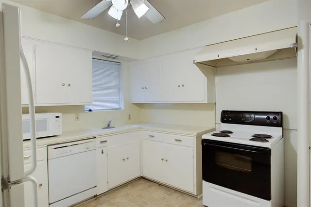 a kitchen with a stove white cabinets and white appliances