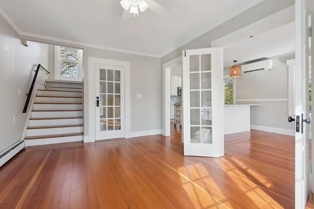 a view of an empty room with wooden floor and a window