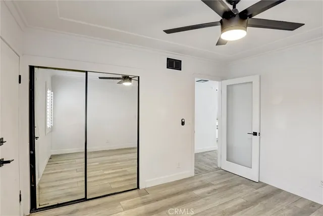 an empty room with wooden floor fan and windows