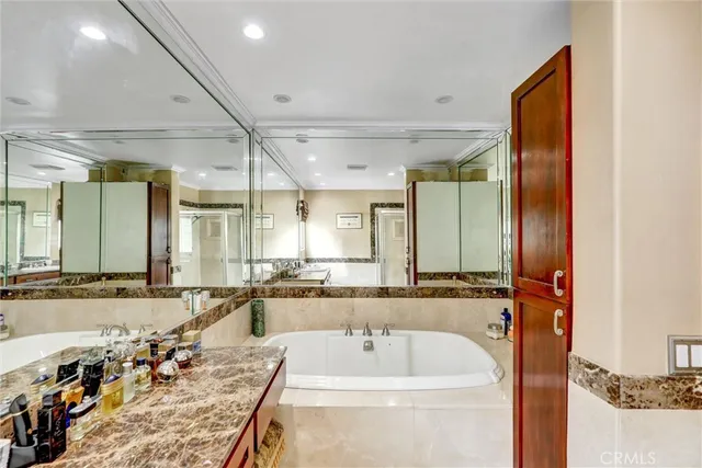 a bathroom with a tub a double vanity sink and mirror
