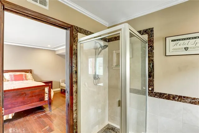 a bedroom with a bed and a glass door shower