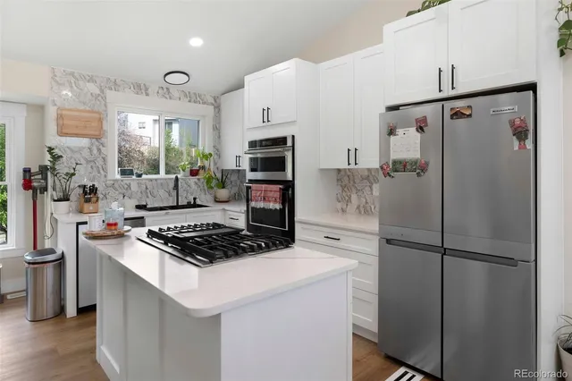 a kitchen with stainless steel appliances granite countertop a refrigerator a sink and a stove