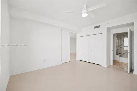 an empty room with closet and a ceiling fan