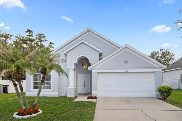 a front view of a house with a yard and palm trees