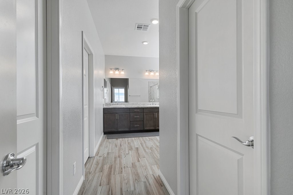 4191 Velvet View Street Las Vegas, NV 89129 - Photo 19 of 44 Bathroom featuring a textured wall, double vanity, and light wood-type flooring
