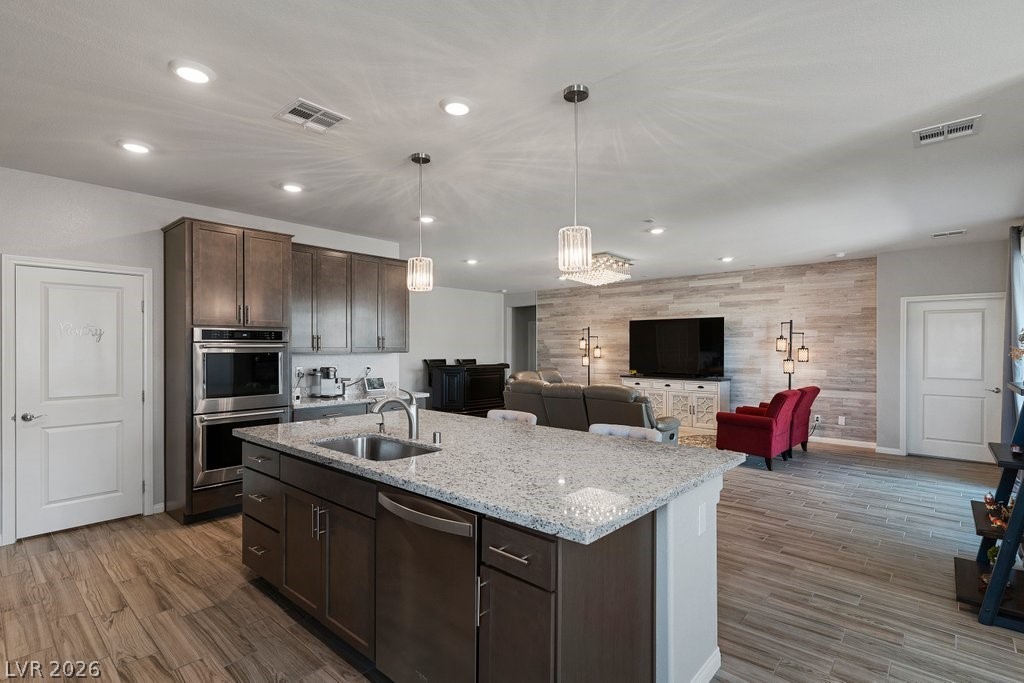 4191 Velvet View Street Las Vegas, NV 89129 - Photo 7 of 44 Kitchen featuring dark wood finish cabinets, light stone counters, stainless steel appliances, and a kitchen island with sink