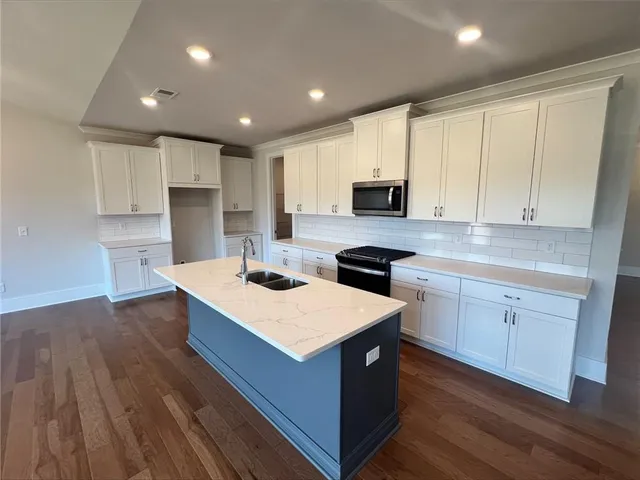 a kitchen with white cabinets sink and stove