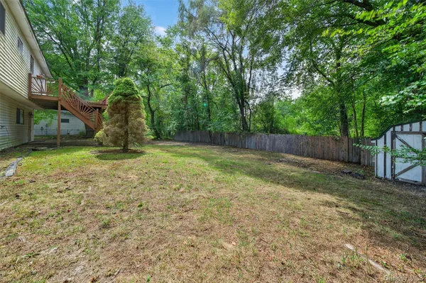 a backyard of a house with lots of plants and large tree