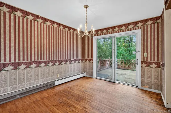 a view of an empty room with wooden floor and windows