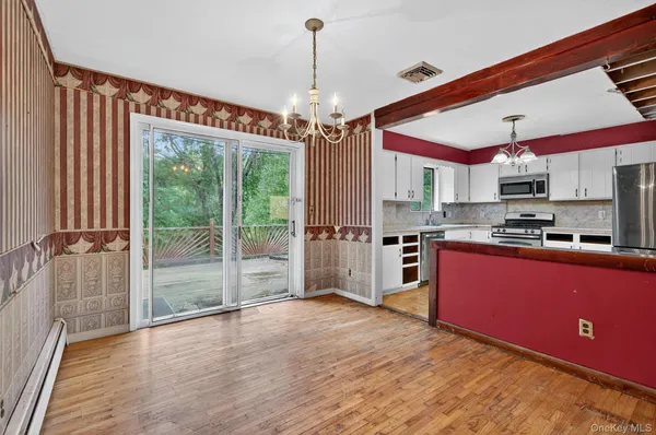 a open kitchen with stainless steel appliances granite countertop a refrigerator a oven a island with a wooden floor