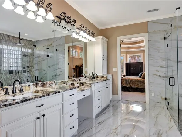 a en suite spacious bathroom with a granite countertop double vanity sink a mirror and shower