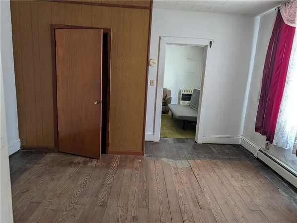 a view of a livingroom with wooden floor and a bedroom