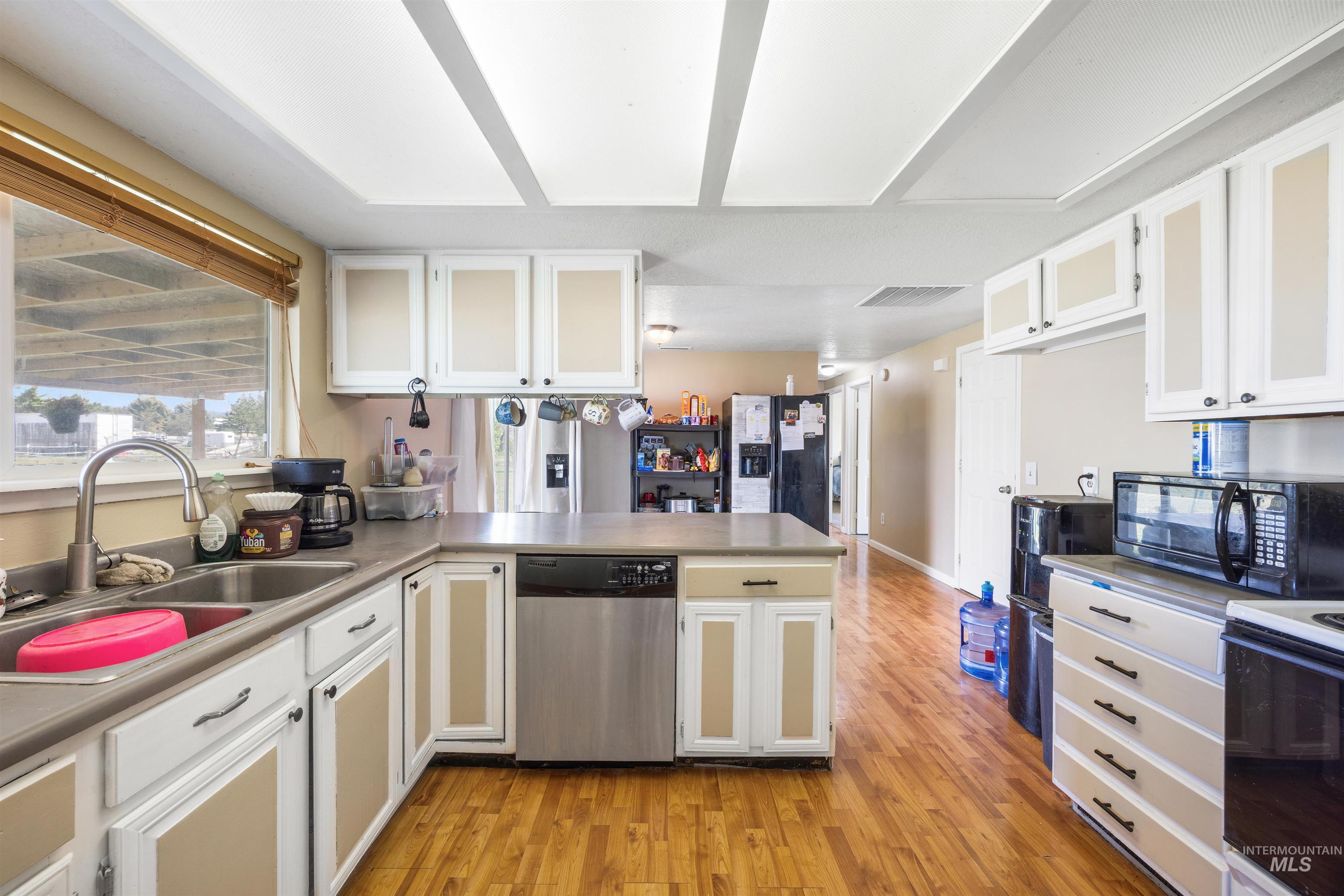 3044 Northeast Reservoir Road Mountain Home, ID 83647 - Photo 11 of 34 Kitchen featuring wood-finish flooring, white cabinetry with tan inserts, stainless steel appliances, and a double basin sink