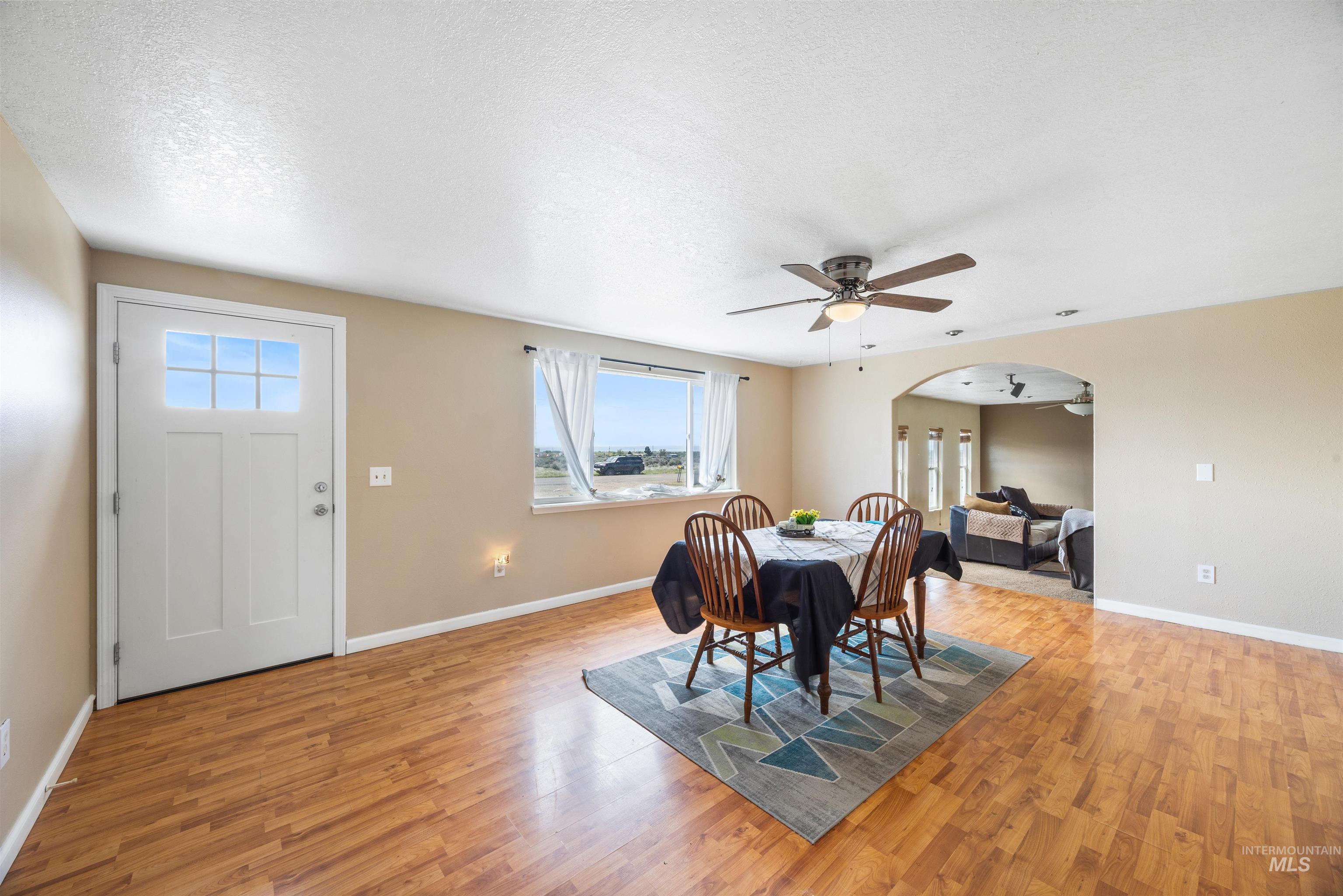 3044 Northeast Reservoir Road Mountain Home, ID 83647 - Photo 14 of 34 Open-concept living space featuring wood-finish flooring, a ceiling fan with integrated lighting, and an arched doorway leading to an additional area