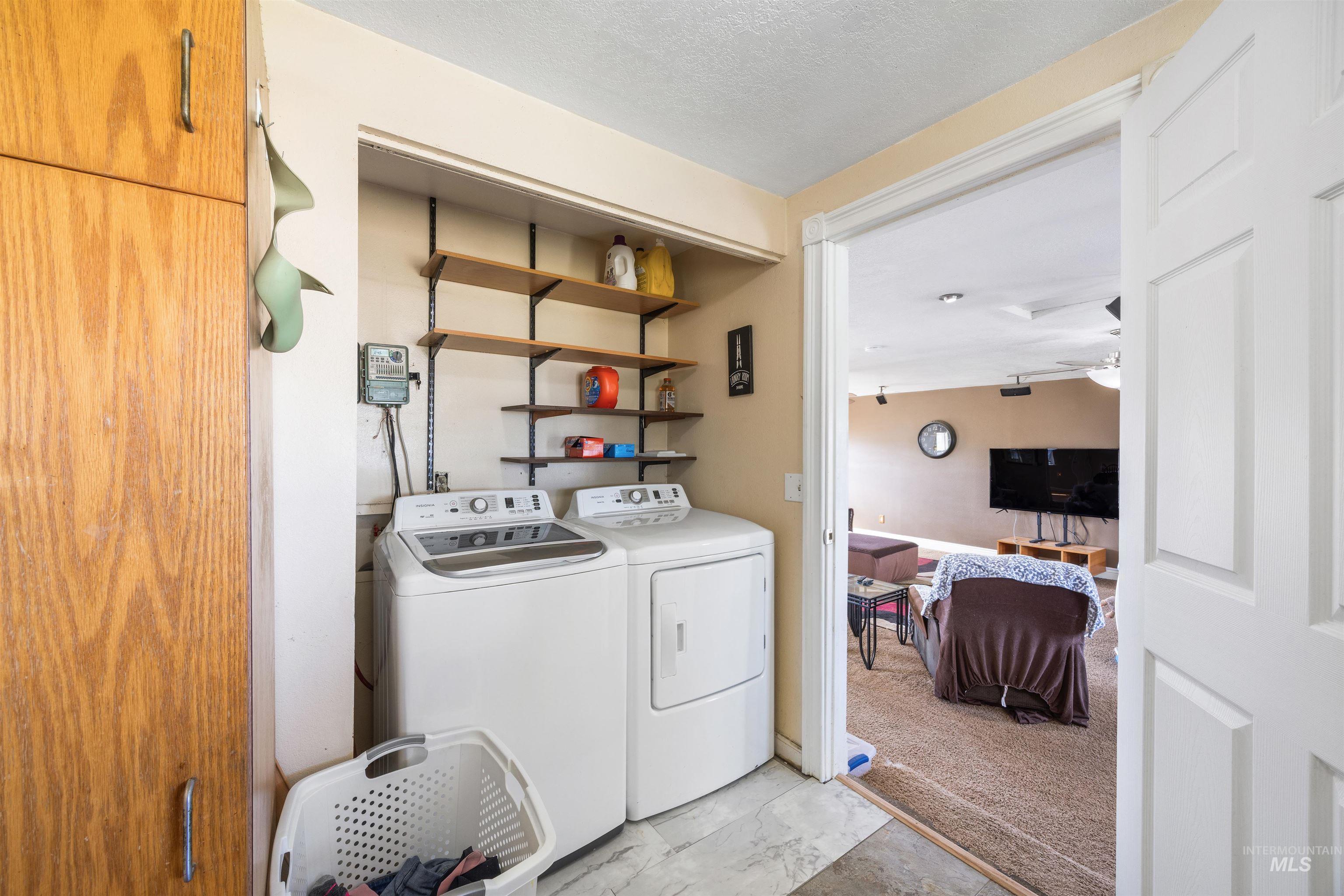3044 Northeast Reservoir Road Mountain Home, ID 83647 - Photo 15 of 34 Dedicated laundry area featuring a full-size washer and dryer, wood-finish cabinetry, and wall-mounted shelving