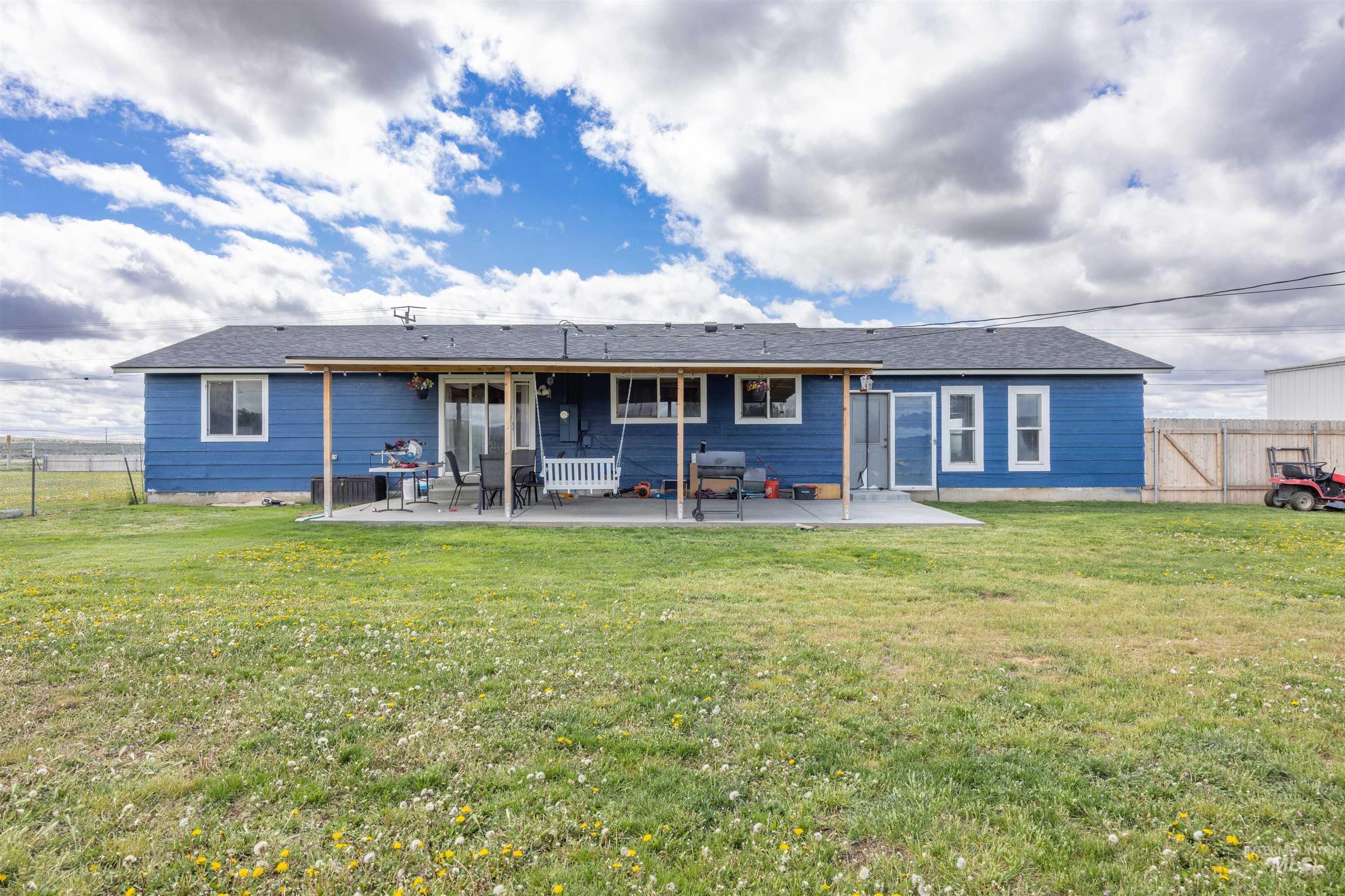 3044 Northeast Reservoir Road Mountain Home, ID 83647 - Photo 19 of 34 Spacious backyard featuring a large concrete patio, full-length patio cover, and blue exterior siding