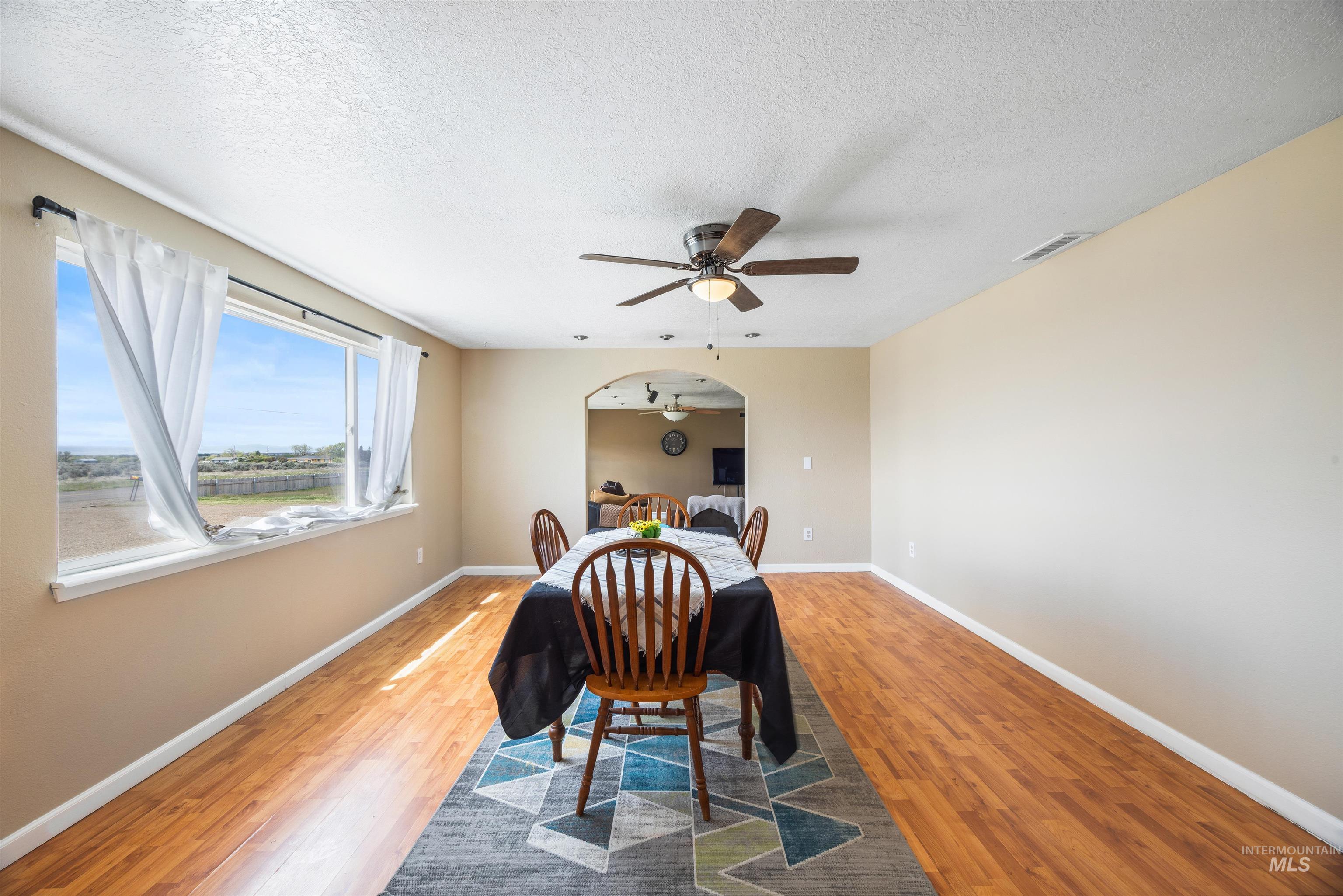 3044 Northeast Reservoir Road Mountain Home, ID 83647 - Photo 20 of 34 Spacious dining area featuring wood-finish flooring, a contemporary ceiling fan, and an expansive window with white trim