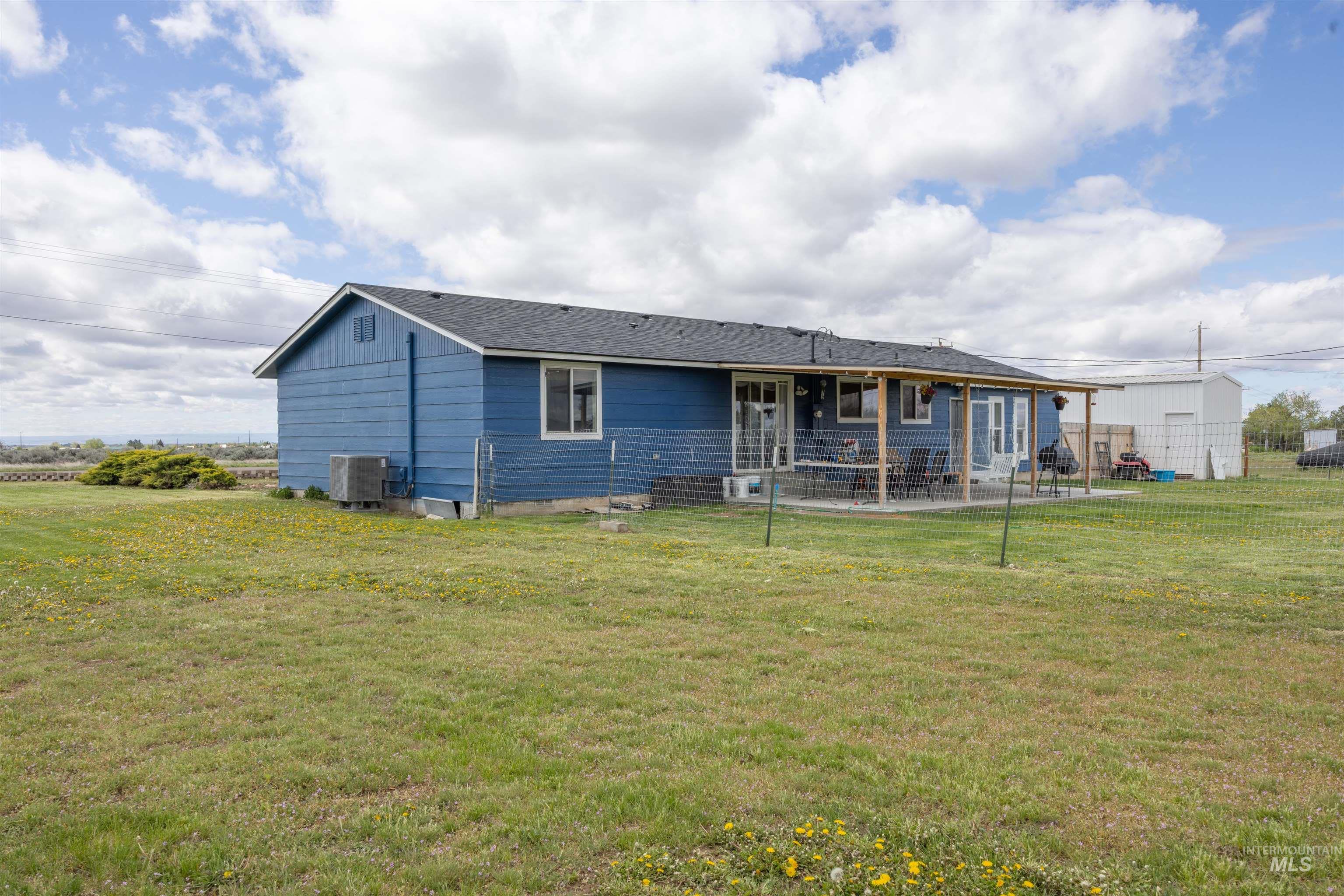 3044 Northeast Reservoir Road Mountain Home, ID 83647 - Photo 27 of 34 Rear exterior featuring blue siding, a dark shingle roof, and multiple windows