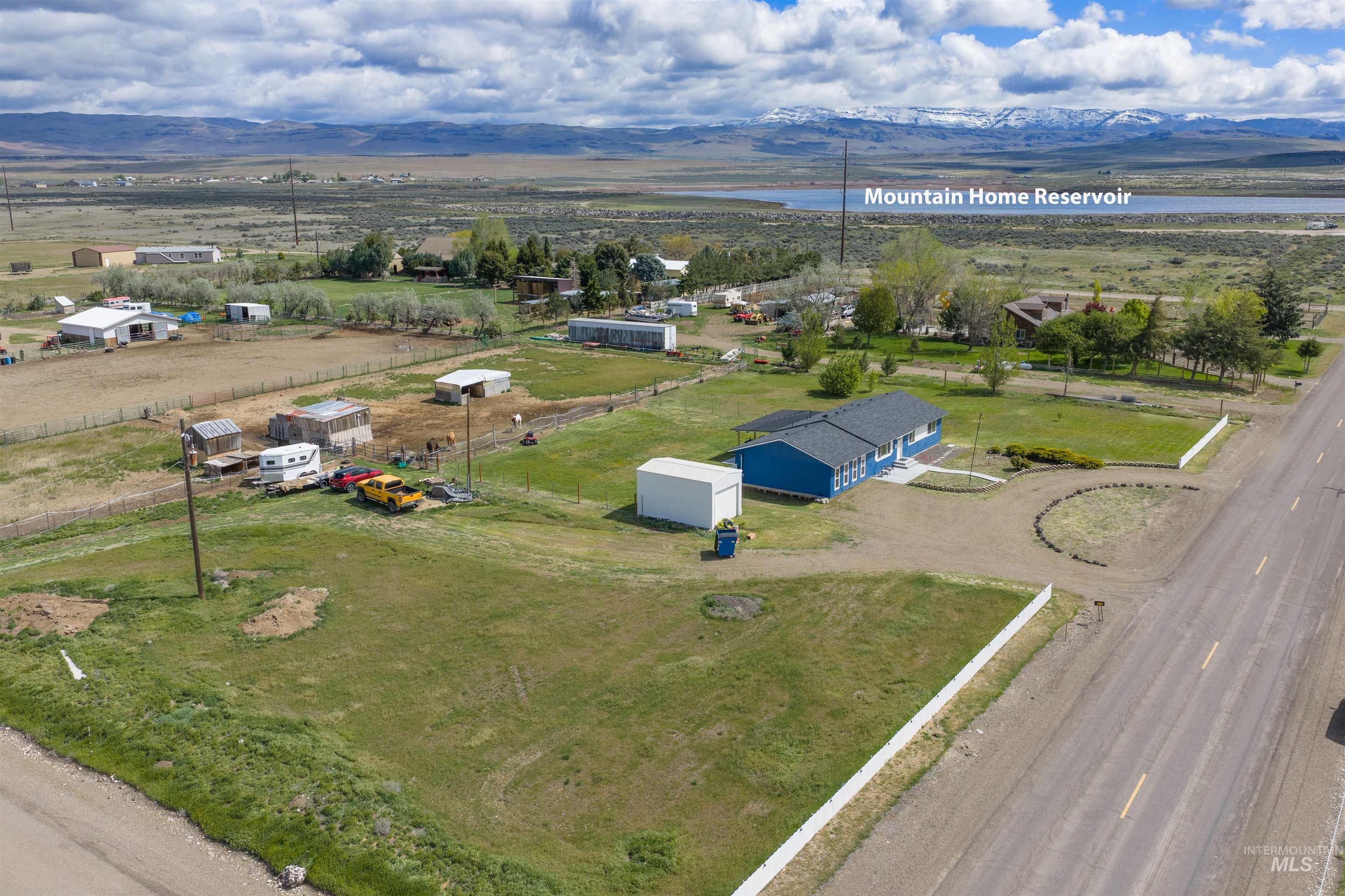 3044 Northeast Reservoir Road Mountain Home, ID 83647 - Photo 30 of 34 Expansive rural property featuring a blue single-story residence with a dark roof, a detached white outbuilding, and a gravel driveway
