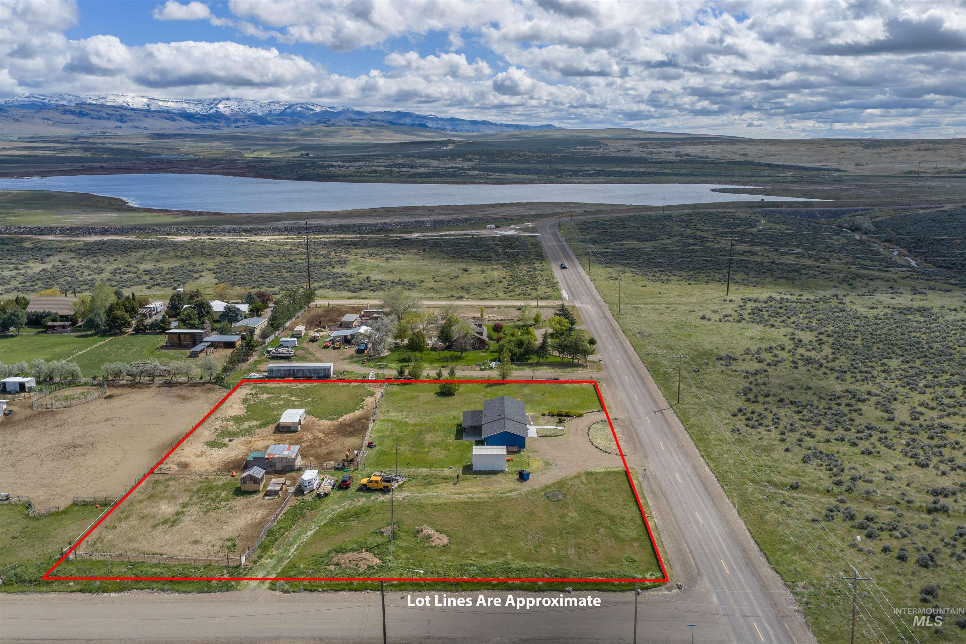 3044 Northeast Reservoir Road Mountain Home, ID 83647 - Photo 33 of 34 Expansive property featuring a blue-sided house with a dark roof, multiple outbuildings, and direct road frontage