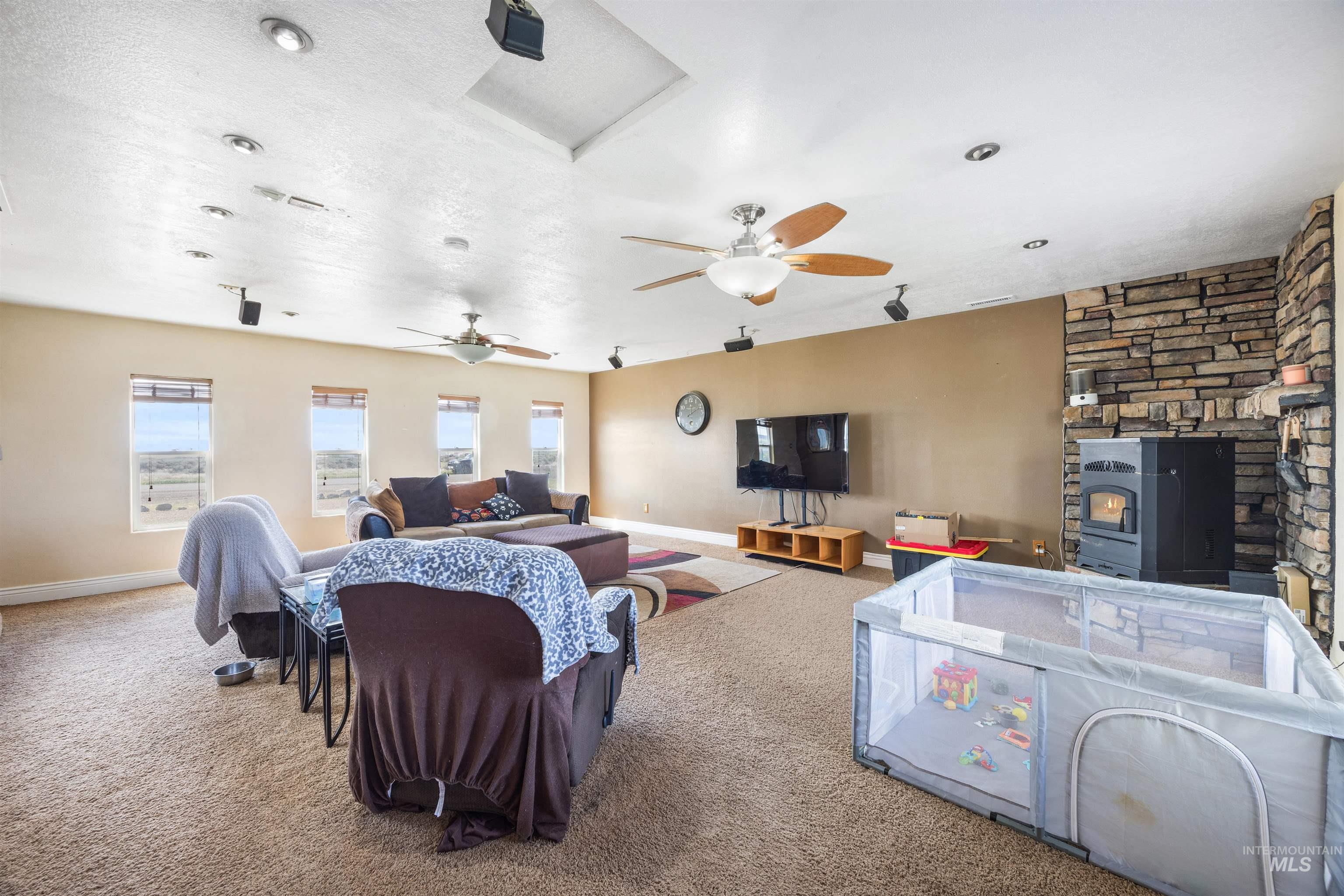 3044 Northeast Reservoir Road Mountain Home, ID 83647 - Photo 6 of 34 Spacious room with recessed lighting, ceiling fans, and a stone-clad fireplace featuring an insert
