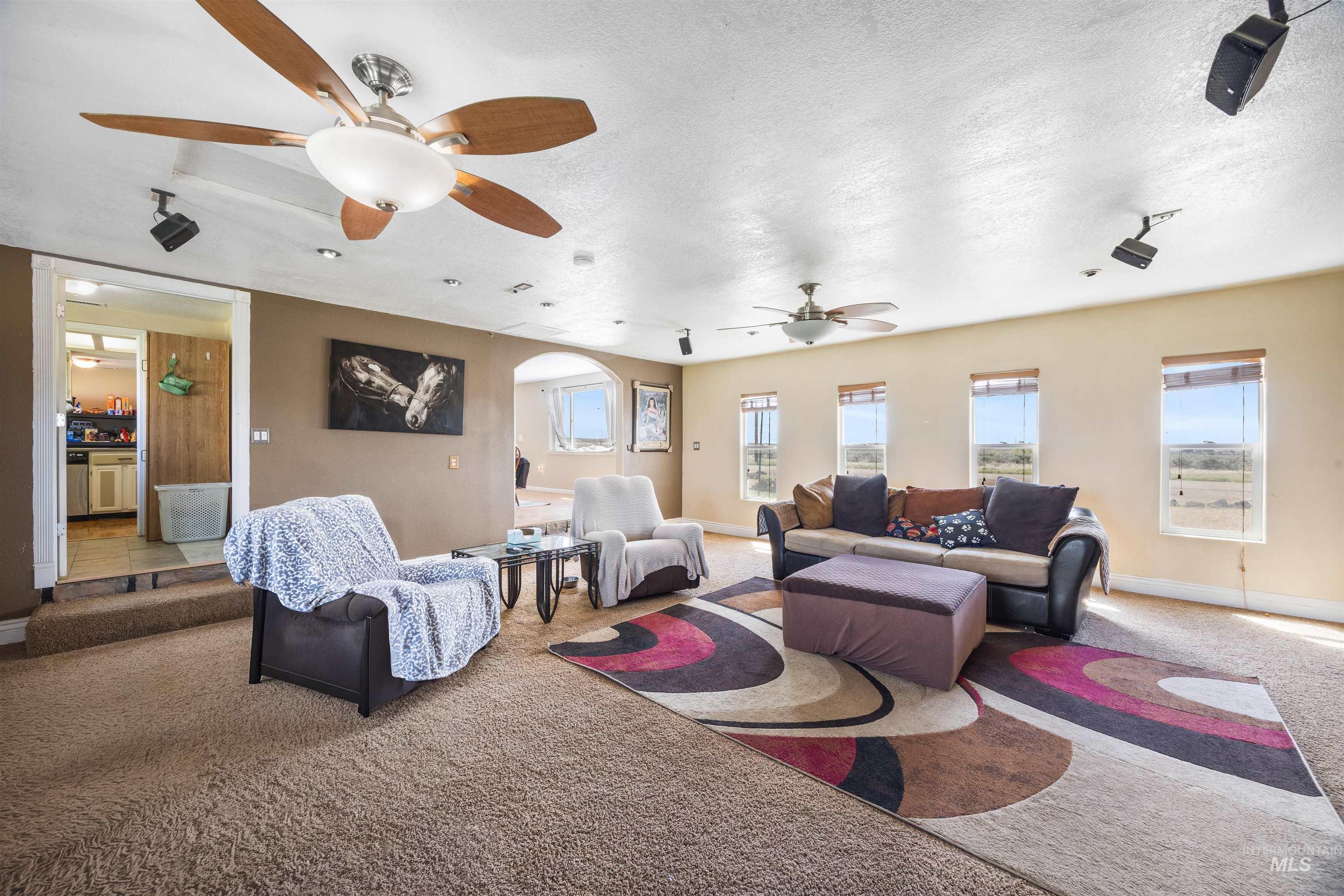 3044 Northeast Reservoir Road Mountain Home, ID 83647 - Photo 7 of 34 Spacious living area featuring carpeted flooring and multiple ceiling fans
