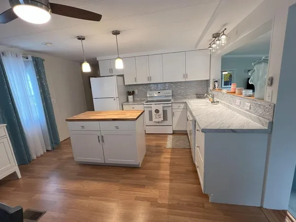 a large kitchen with stainless steel appliances granite countertop a sink stove and wooden floor