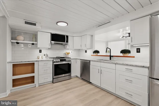 a kitchen with white cabinets and appliances