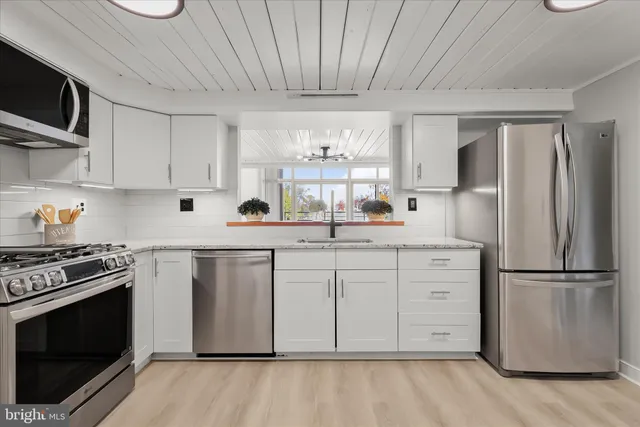 a kitchen with white cabinets stainless steel appliances and wooden floor