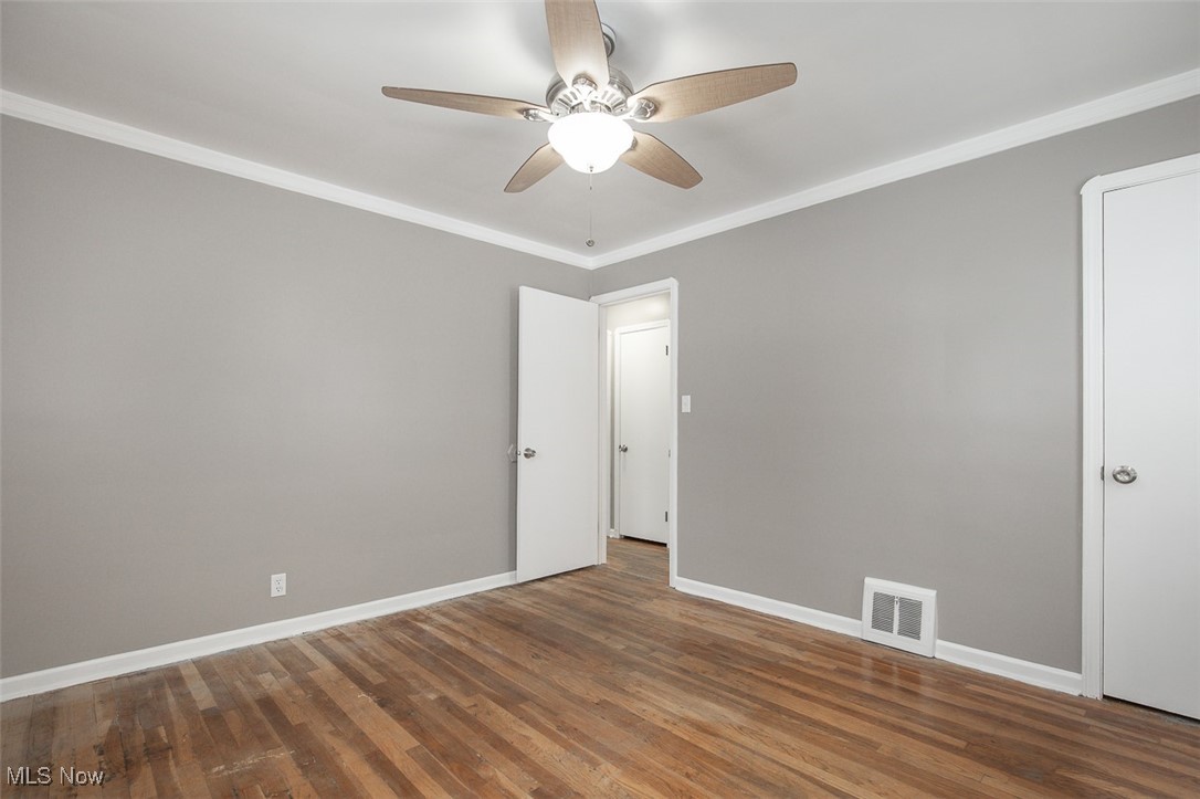 12328 Granger Road Cleveland, OH 44125 - Photo 12 of 37 Unfurnished room featuring crown molding, wood finished floors, and ceiling fan