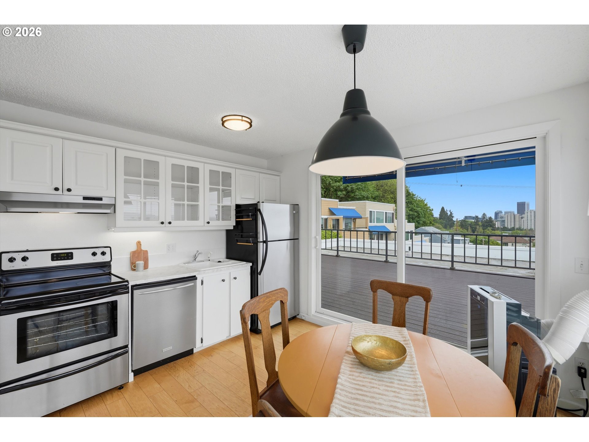3515 Southwest Barbur Boulevard, Unit X3 Portland, OR 97239 - Photo 4 of 33 a kitchen with stainless steel appliances granite countertop a stove a refrigerator a dining table and chairs with wooden floor