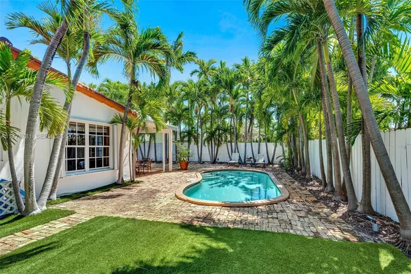 a view of a backyard with potted plants and large trees