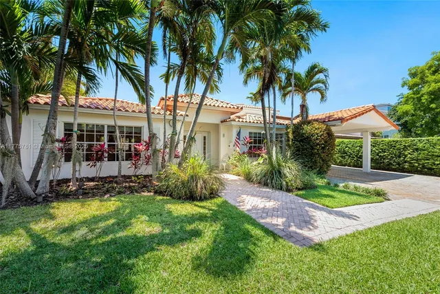 a view of a house with a yard and palm trees