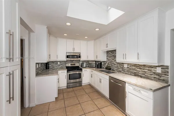 a kitchen with granite countertop stainless steel appliances and white cabinets