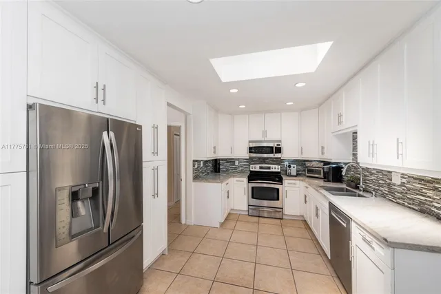 a kitchen with stainless steel appliances granite countertop a refrigerator stove and sink