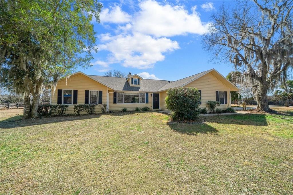 a front view of a house with yard porch and a tree