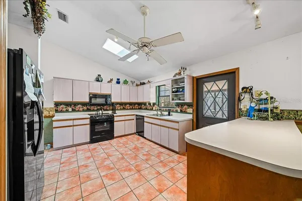 a kitchen with stainless steel appliances granite countertop a stove top oven a sink a dining table and chairs with wooden floor