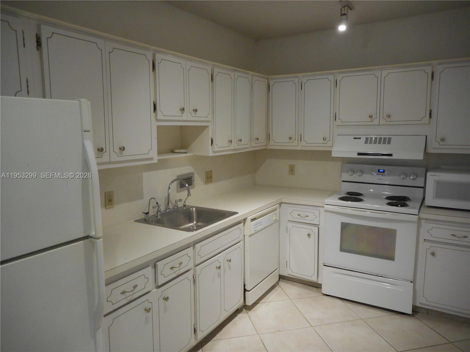 10185 Collins Avenue, Unit 1002 Bal Harbour, FL 33154 - Photo 14 of 27 a kitchen with white cabinets and white appliances