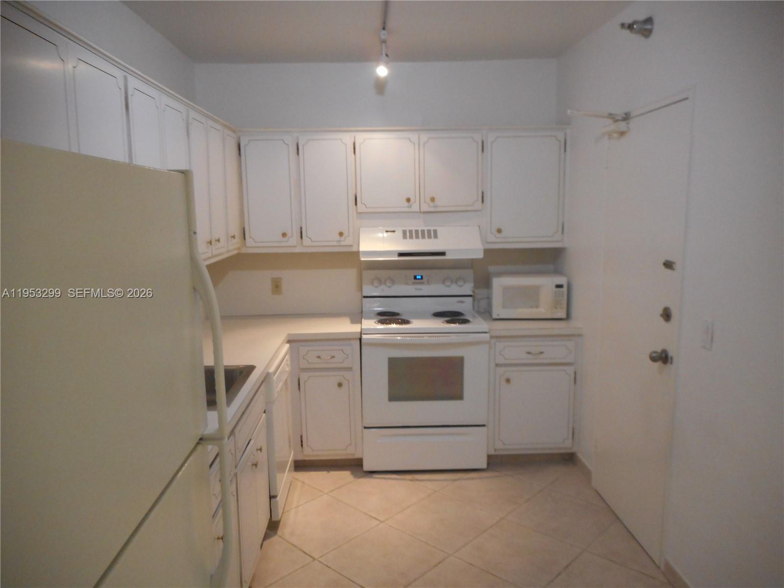 10185 Collins Avenue, Unit 1002 Bal Harbour, FL 33154 - Photo 15 of 27 a kitchen with white cabinets and white appliances