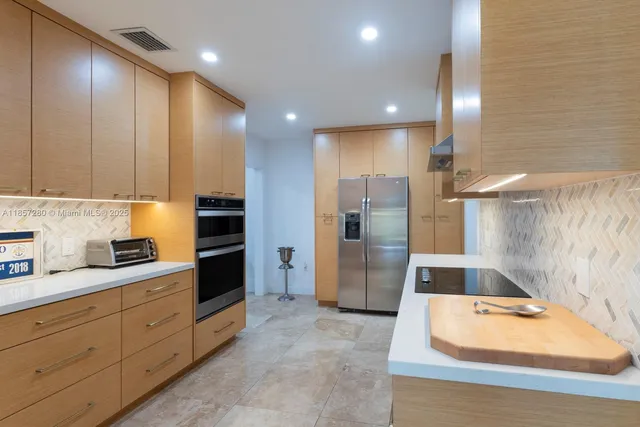 a kitchen with stainless steel appliances kitchen island granite countertop a refrigerator and a sink