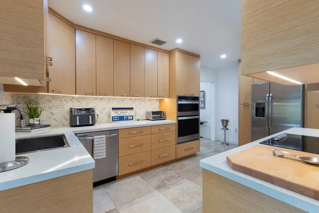 a kitchen with stainless steel appliances kitchen island granite countertop a sink a stove and a refrigerator
