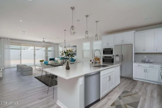 a kitchen with stainless steel appliances kitchen island granite countertop a sink a stove a dining table and chairs with wooden floor