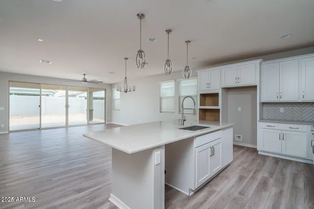 a large kitchen with stainless steel appliances granite countertop a sink a oven and white cabinets with wooden floor