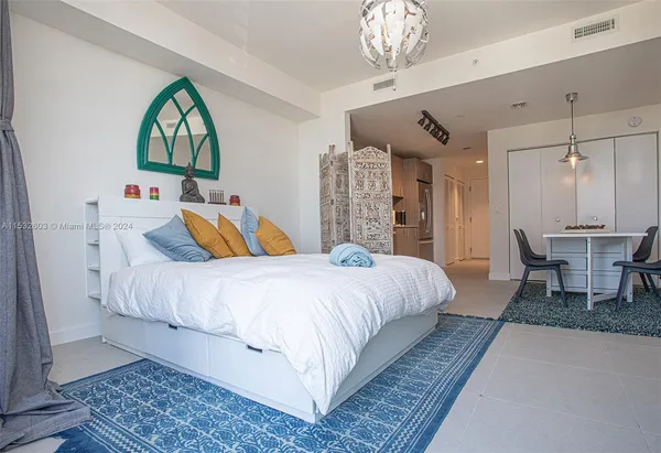 a spacious bedroom with a large bed and a chandelier