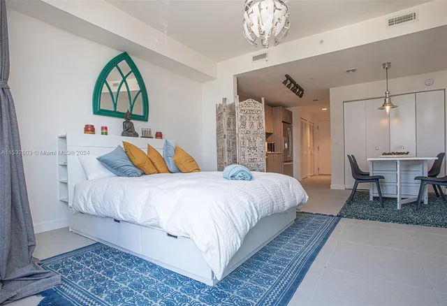 a spacious bedroom with a large bed and a chandelier